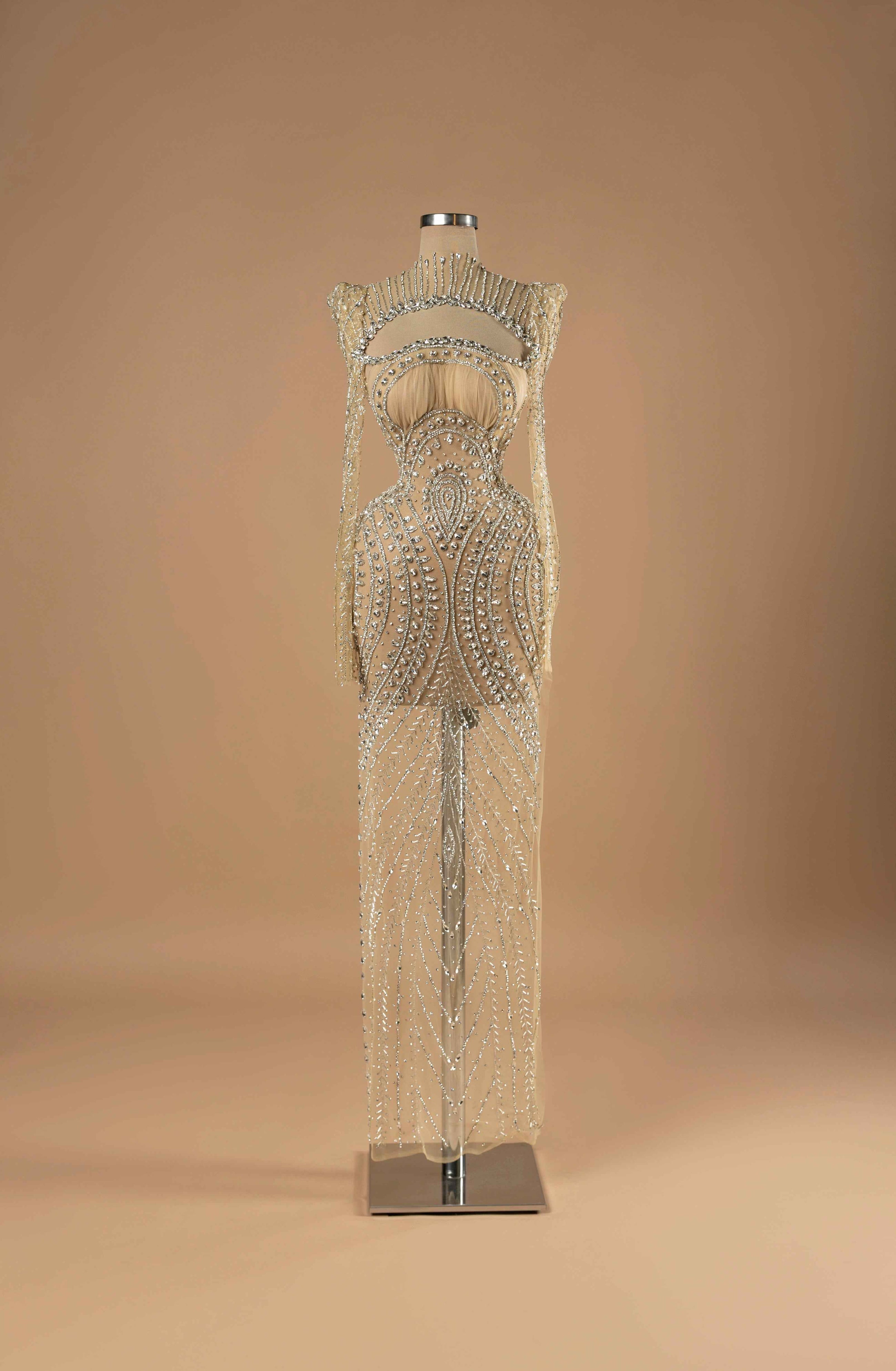 Sihëna Starlit Symphony — nude high-neck long-sleeve column evening gown in sheer crystal-beaded illusion tulle with an open chest cutout.