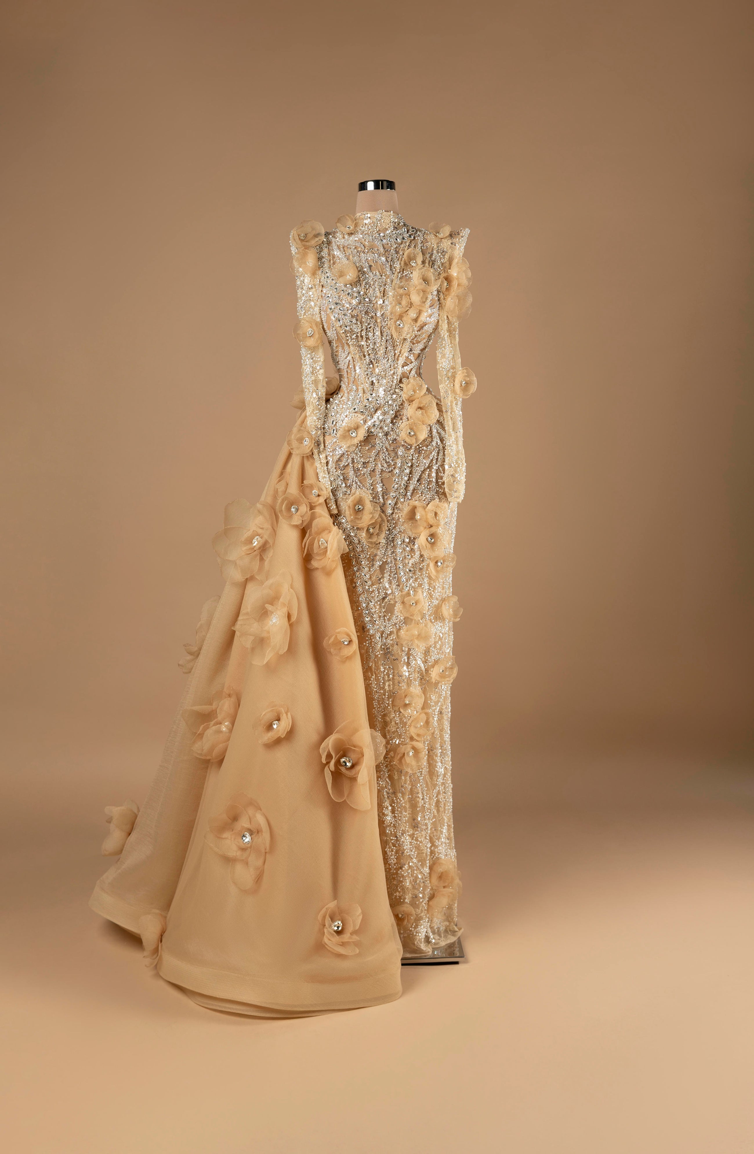 Sihëna Golden Blossom Cascade — champagne high-neck long-sleeve column evening gown with silver crystal beadwork, 3D organza florals and cascading overskirt train.