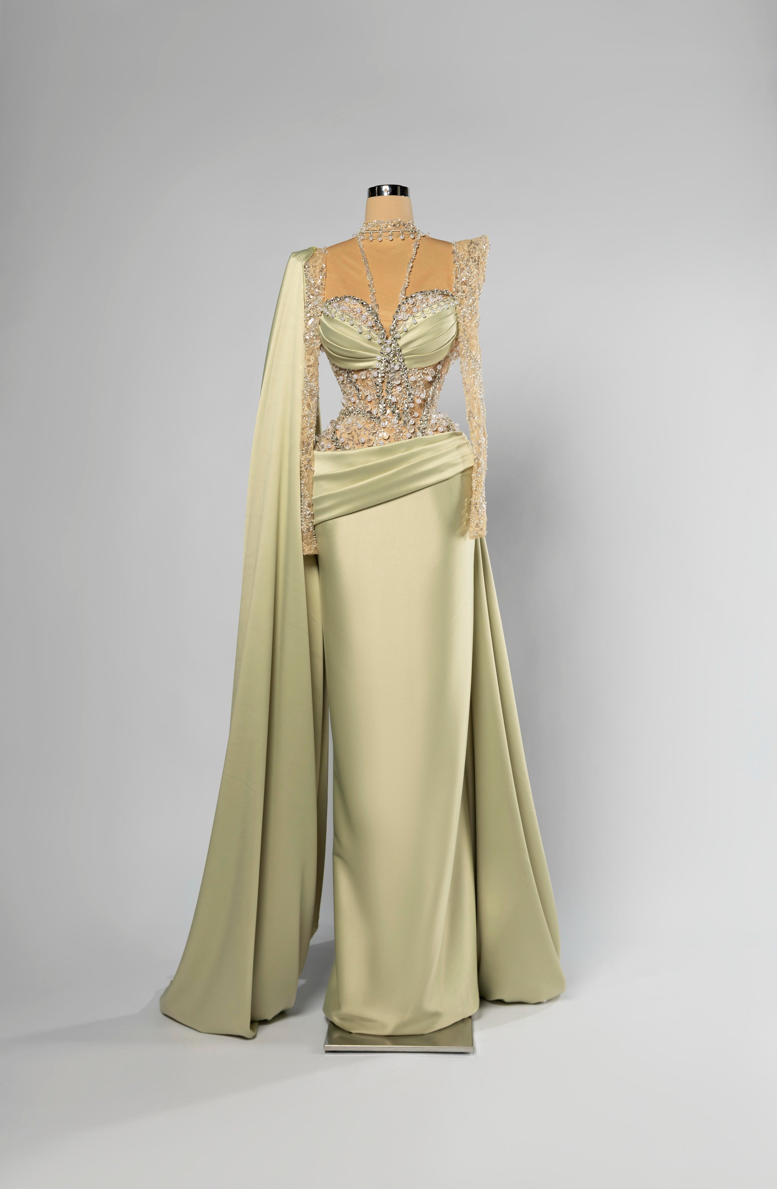 Sihëna Elysian Sage — sage-green high-neck long-sleeve column evening gown in satin with crystal-pearl illusion bodice and shoulder cape.