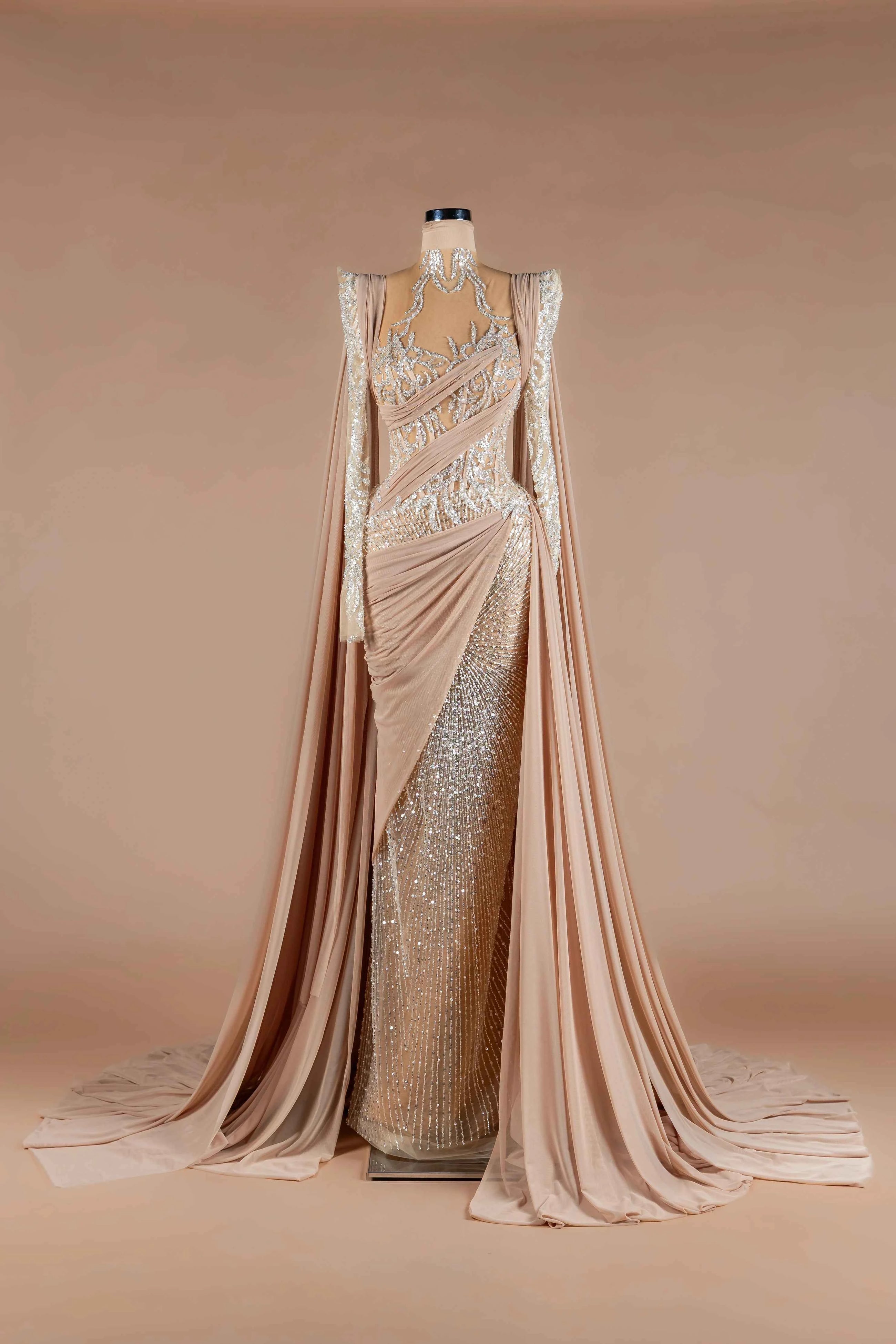 Sihëna Nude Athena — nude high-neck long-sleeve mermaid gown with silver sequin beadwork, draped chiffon sash and high slit.