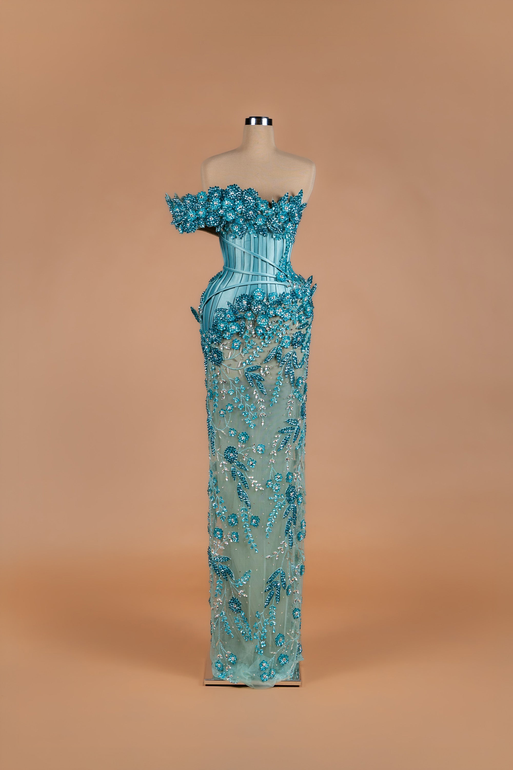 Sihëna Aqua Bloom — teal off-shoulder mermaid gown with 3D crystal floral band, corset bodice and beaded sheer skirt.