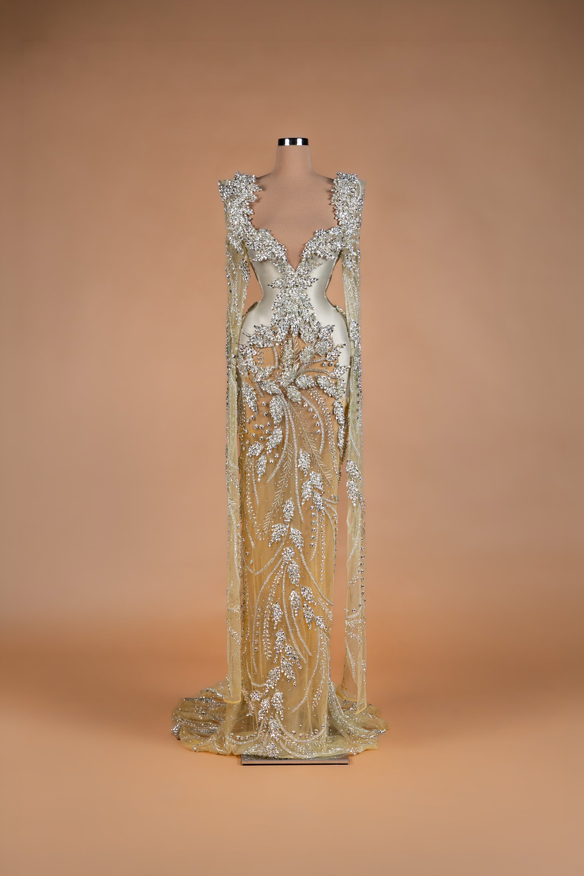Sihëna Silver Wheat — champagne v-neck caped silver-crystal mermaid gown with beaded wheat motifs and sheer skirt.