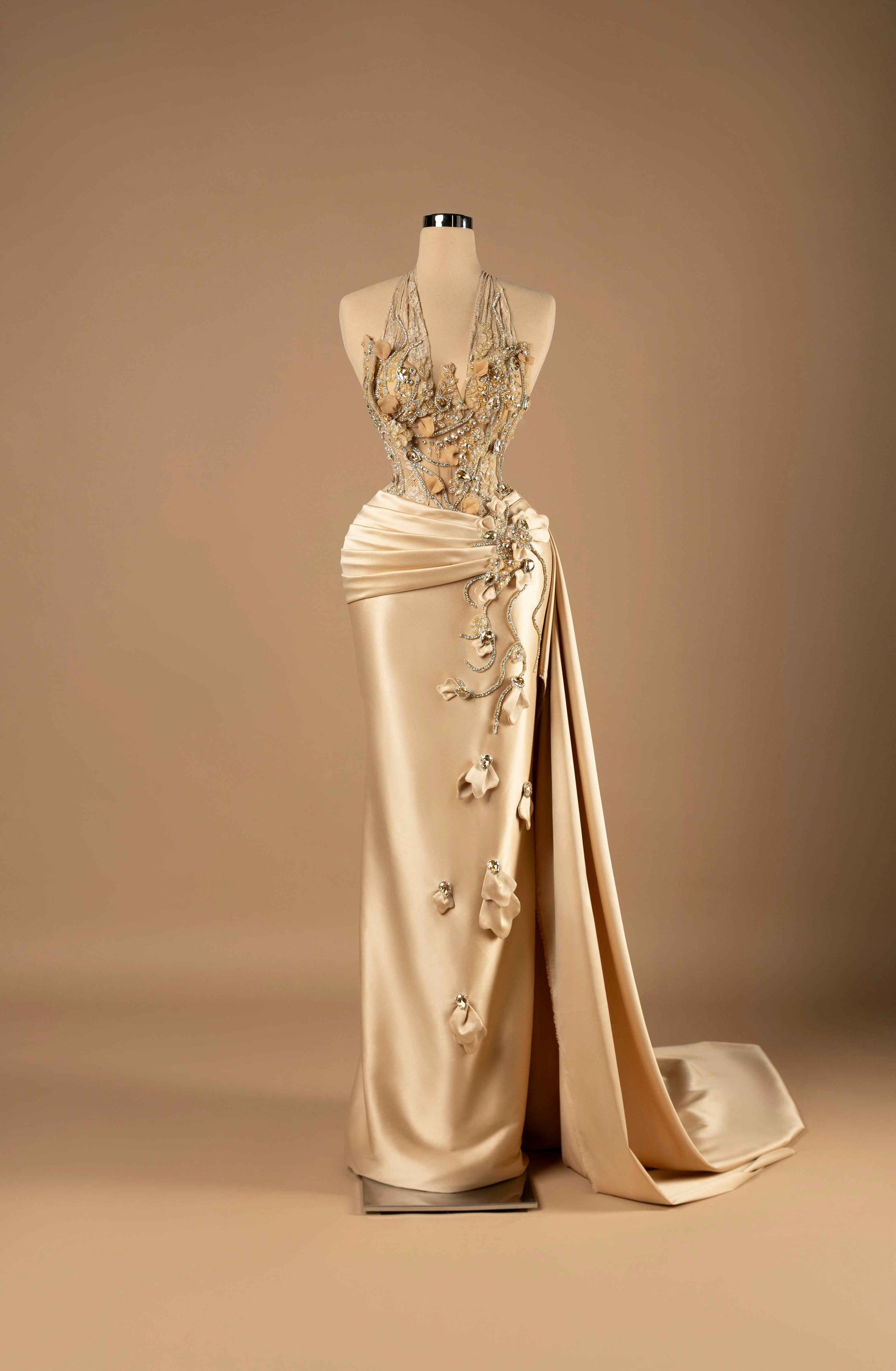 Sihëna Golden Petal Harmony — champagne halter sleeveless column gown with crystal-beaded illusion bodice, 3D florals and draped satin overskirt with slit.