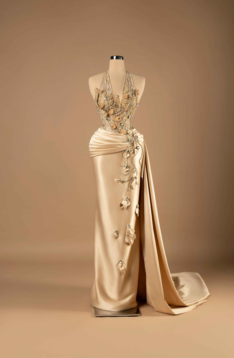 Sihëna Golden Petal Harmony — champagne halter sleeveless column gown with crystal-beaded illusion bodice, 3D florals and draped satin overskirt with slit.