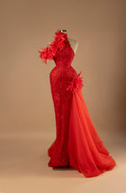 Sihëna Scarlet Inferno — red one-shoulder sleeveless mermaid evening gown with red feather floral appliqués, crystal beading and organza overskirt train.