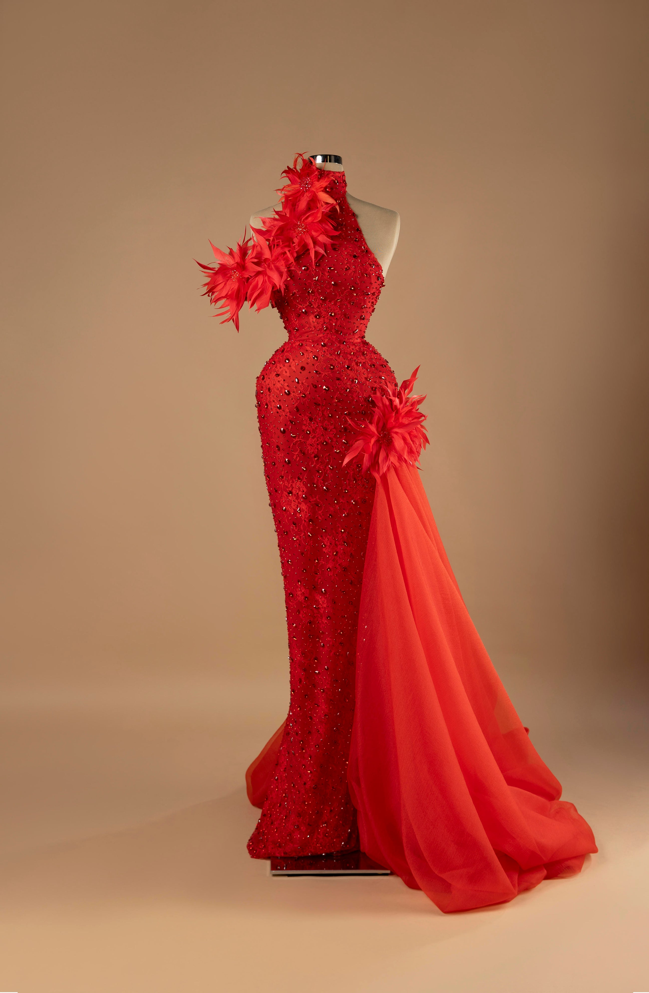 Sihëna Scarlet Inferno — red one-shoulder sleeveless mermaid evening gown with red feather floral appliqués, crystal beading and organza overskirt train.