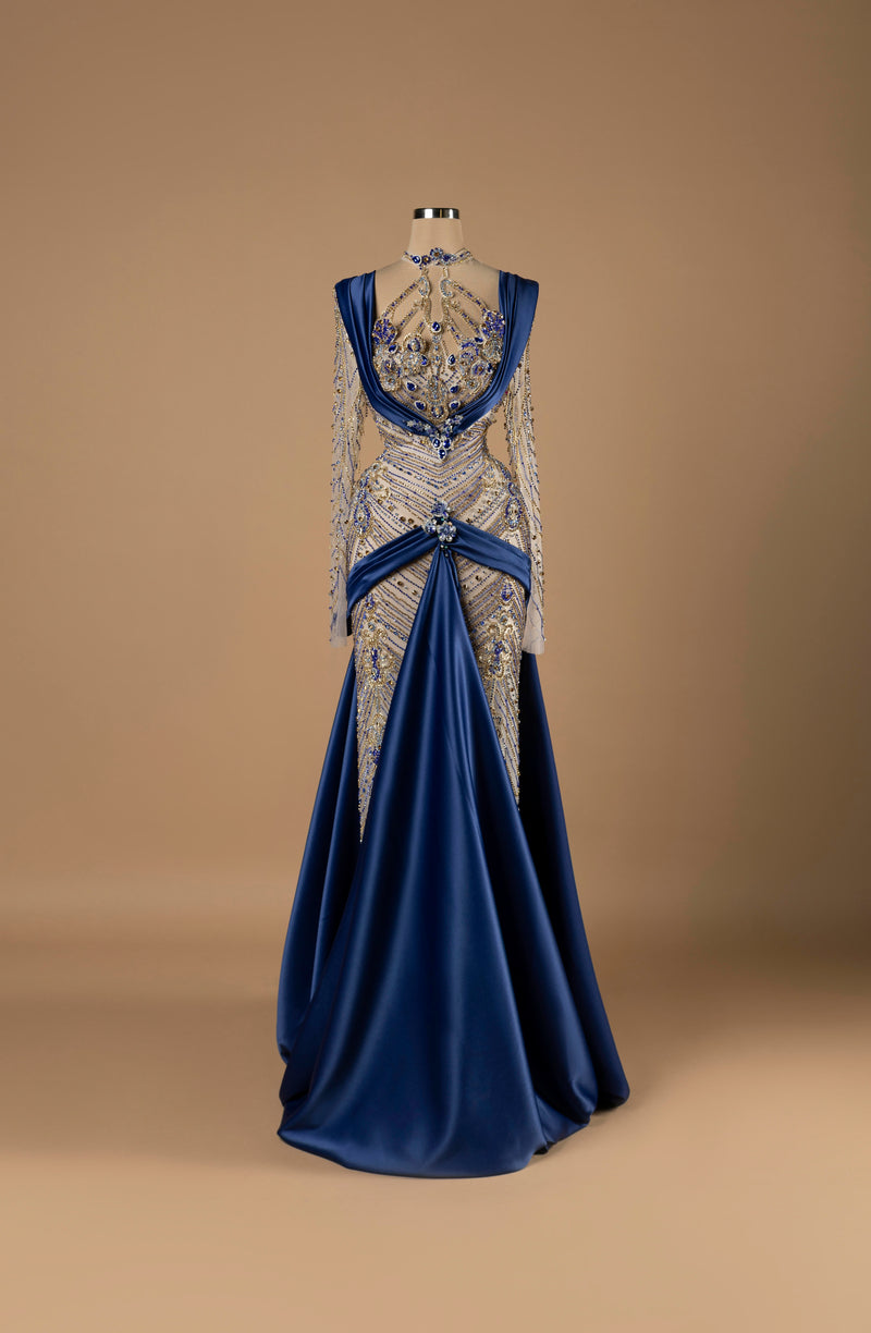 Sihëna Sapphire Majesty — navy high-neck long-sleeve A-line evening gown with sapphire and gold crystal beadwork over illusion bodice and draped satin overskirt.