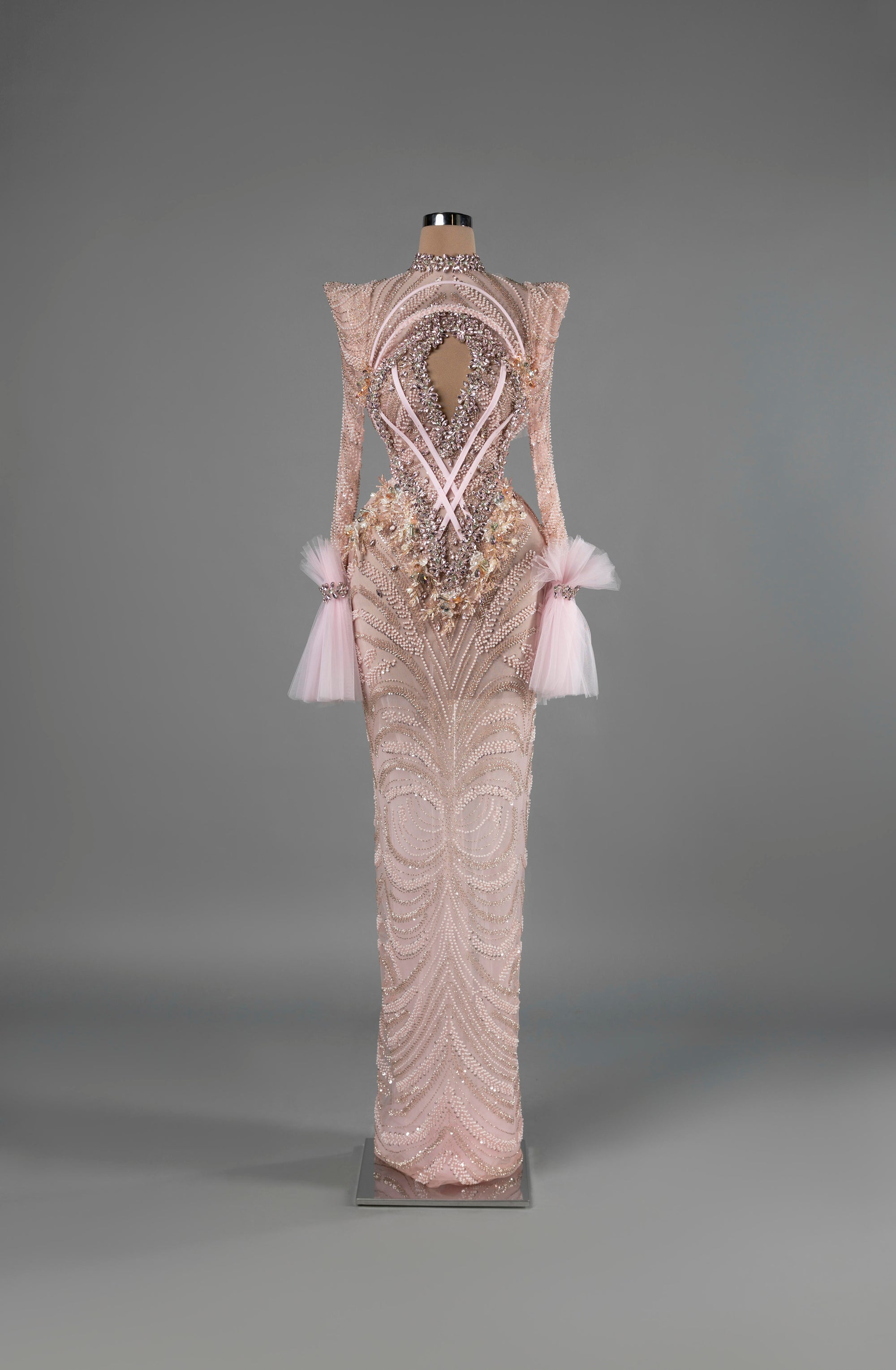Sihëna Blush Enigma — blush high-neck long-sleeve column gown with pearl-crystal beadwork, a chest cutout and tulle cuffs.