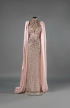 Sihëna Celestial Bloom — blush halter column gown with a deep keyhole, crystal-pearl beadwork on net and a chiffon cape.