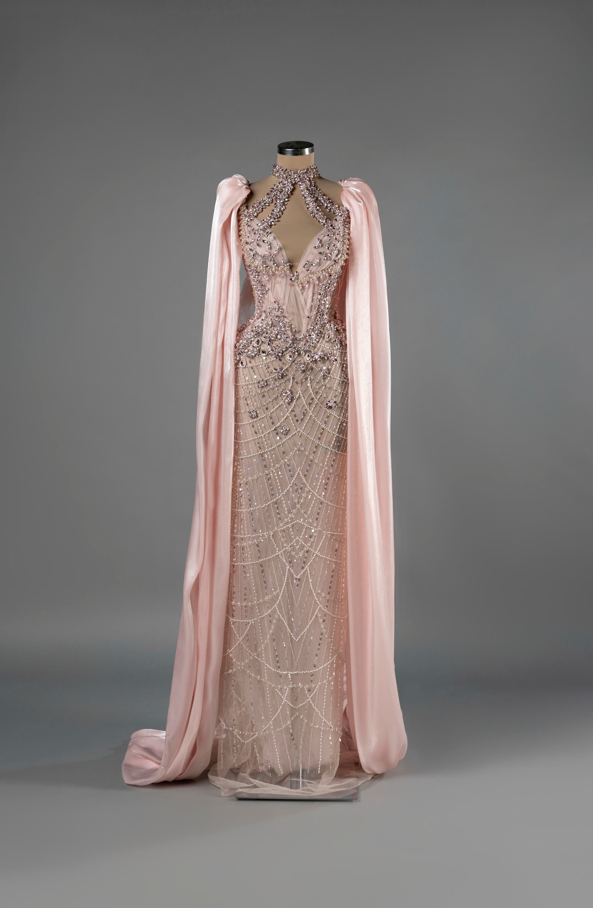 Sihëna Celestial Bloom — blush halter column gown with a deep keyhole, crystal-pearl beadwork on net and a chiffon cape.