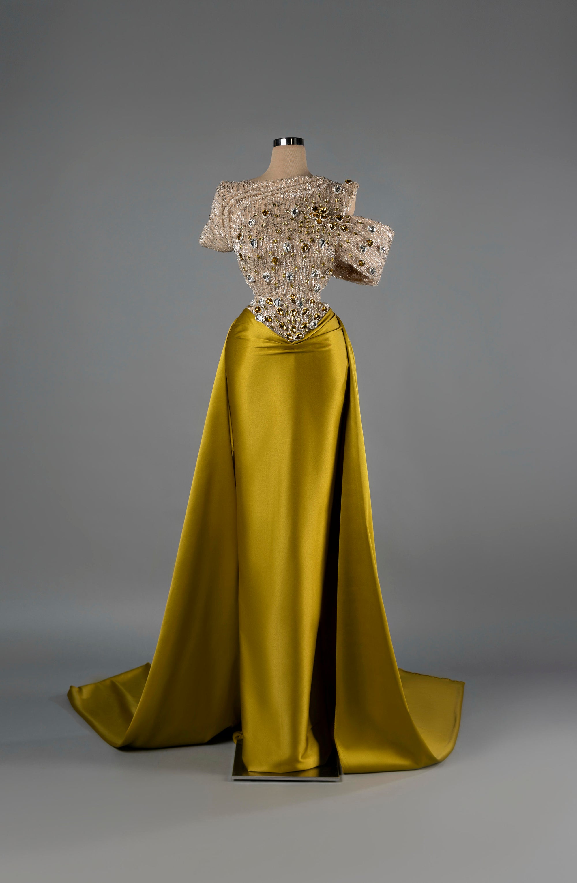 Sihëna Golden Majesty — gold off-shoulder mermaid gown with a crystal-beaded sheer bodice and a satin overskirt and slit.