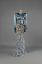 Sihëna Sapphire Enigma — powder-blue high-neck long-sleeve satin mermaid gown with sheer panels and blue crystal beadwork.