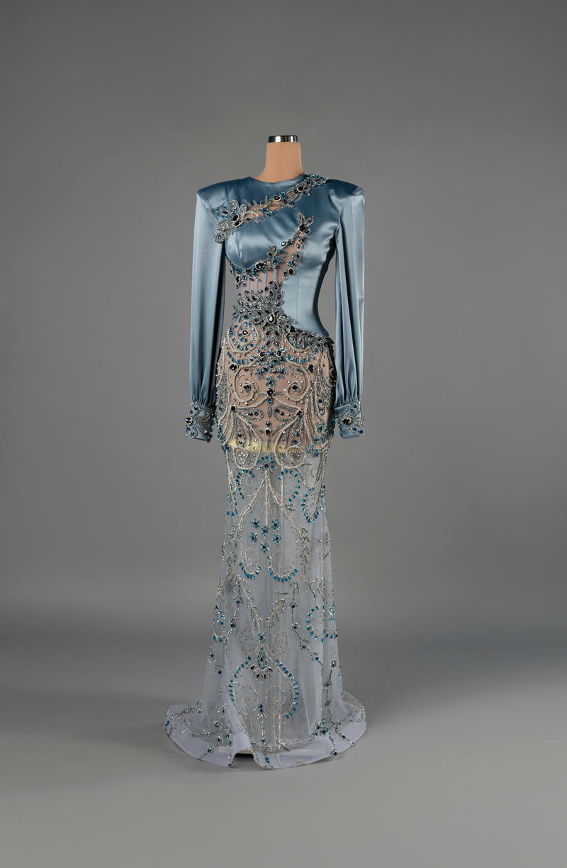 Sihëna Sapphire Enigma — powder-blue high-neck long-sleeve satin mermaid gown with sheer panels and blue crystal beadwork.