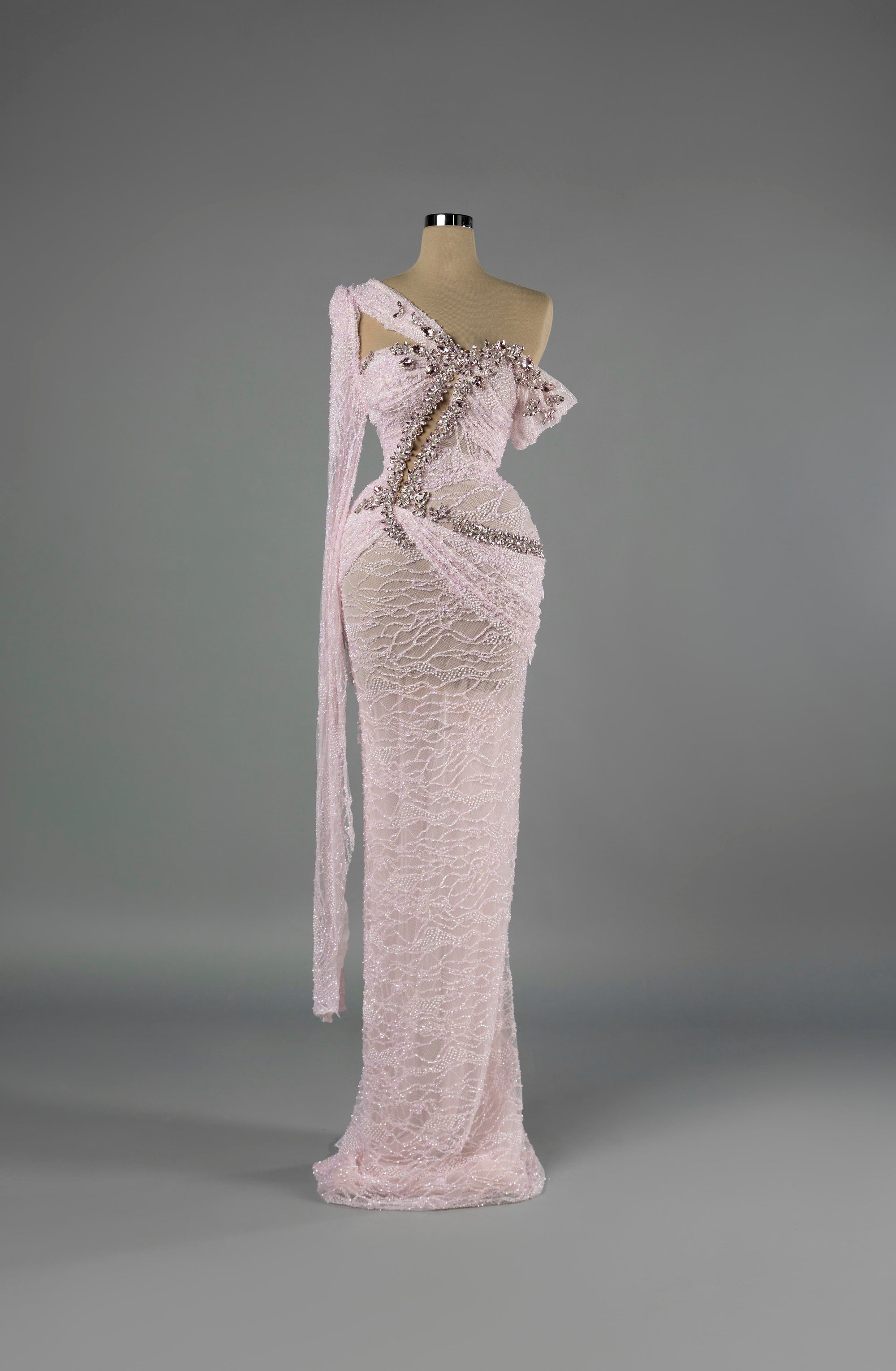 Sihëna Petal Rapture — blush one-shoulder column gown in beaded lace with pink crystal and pearl beadwork over a sheer base.