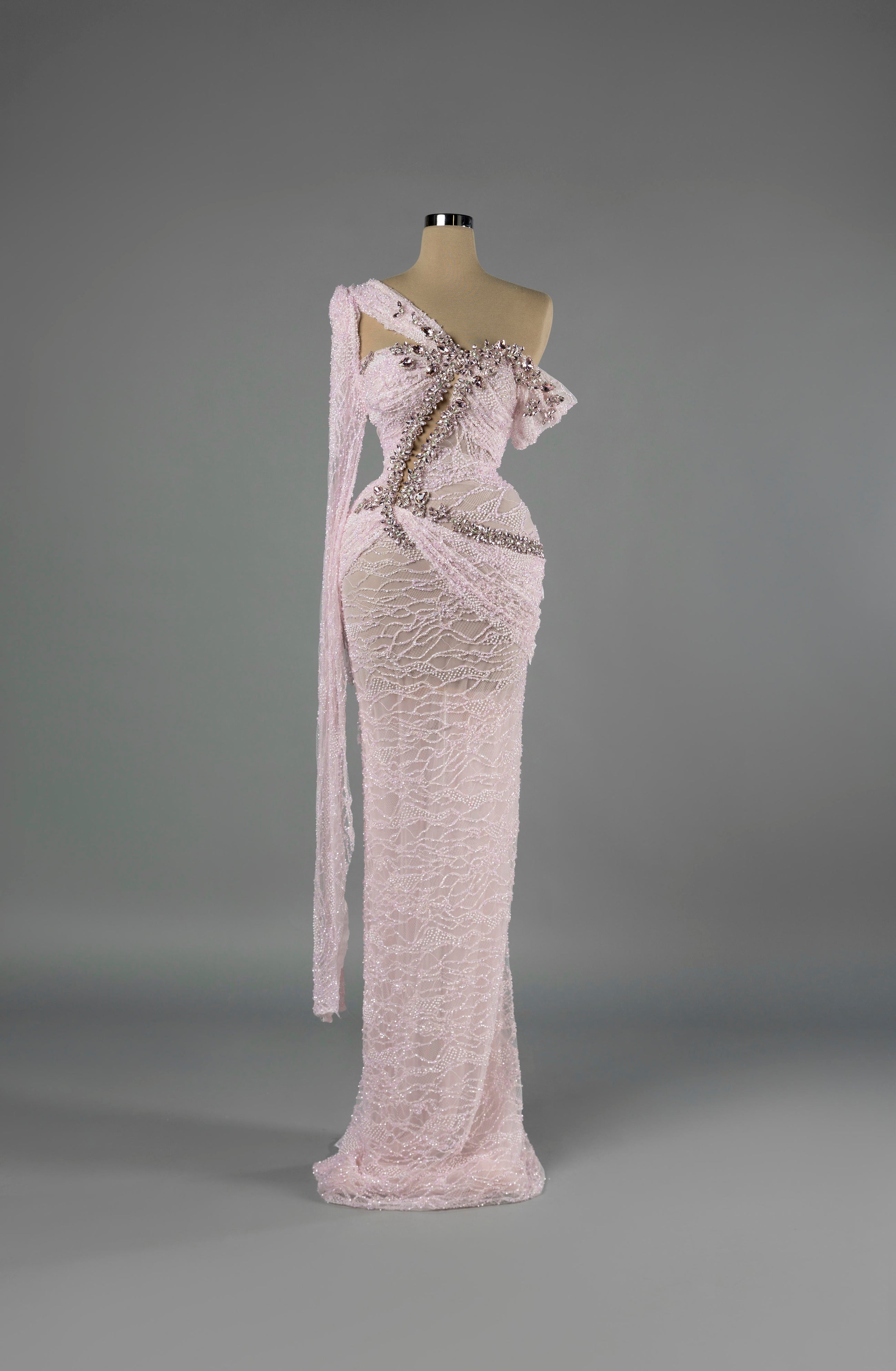 Sihëna Petal Rapture — blush one-shoulder column gown in beaded lace with pink crystal and pearl beadwork over a sheer base.
