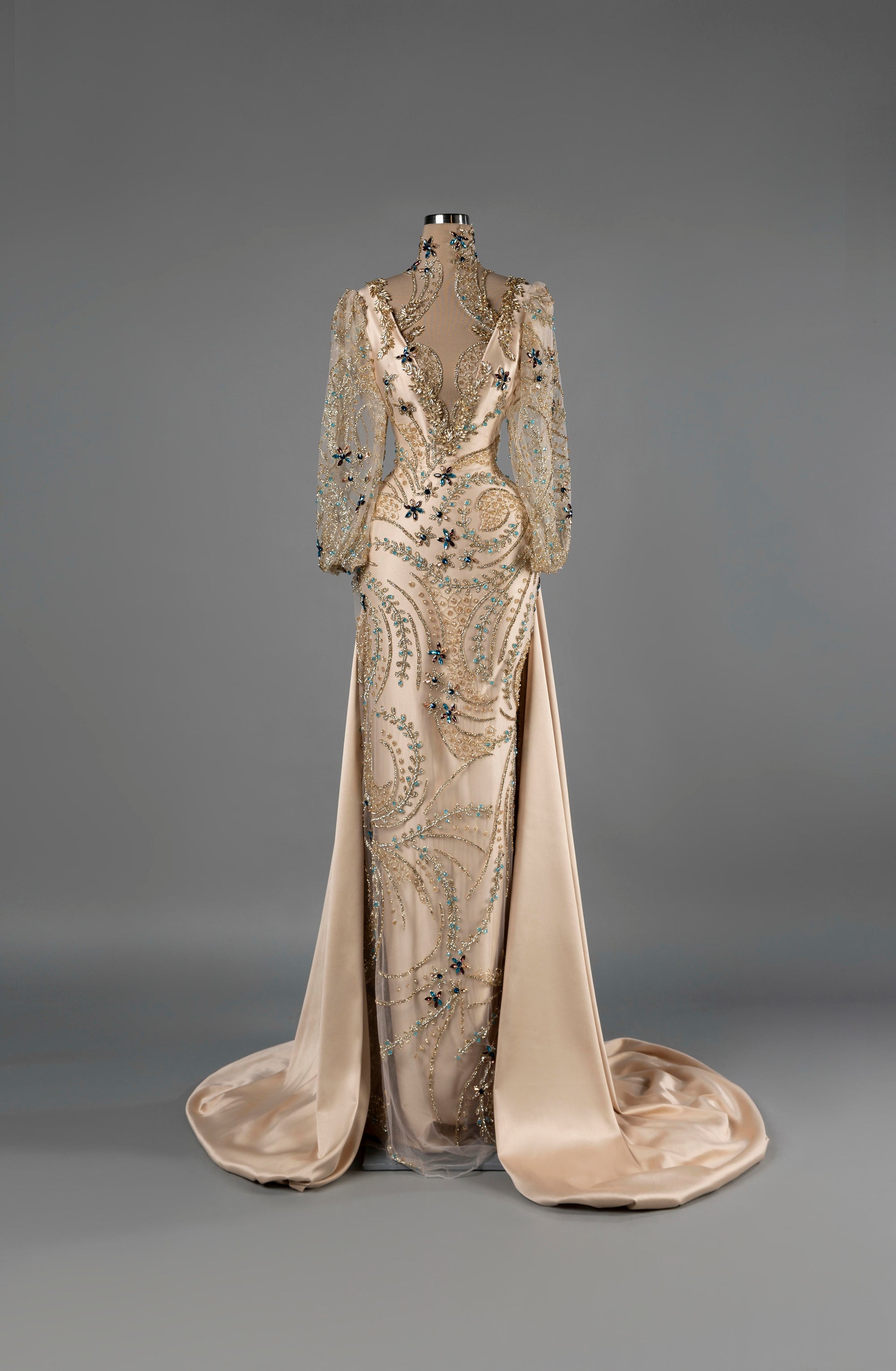 Sihëna Aurora Grace — champagne deep-V long-sleeve mermaid gown with gold crystal beadwork and a satin overskirt.