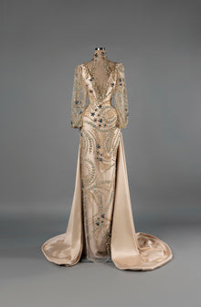 Sihëna Aurora Grace — champagne deep-V long-sleeve mermaid gown with gold crystal beadwork and a satin overskirt.
