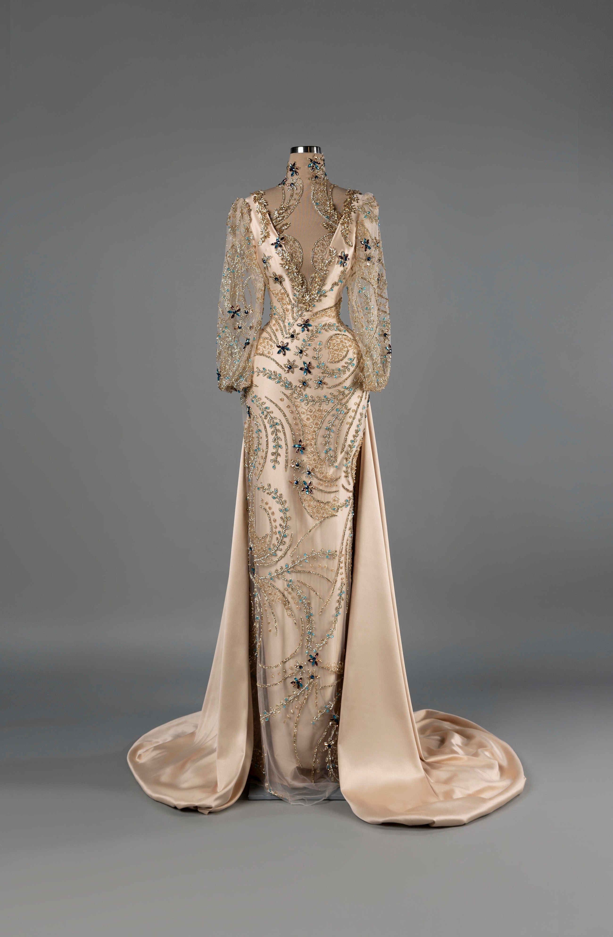 Sihëna Aurora Grace — champagne deep-V long-sleeve mermaid gown with gold crystal beadwork and a satin overskirt.