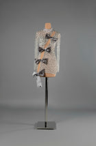 Sihëna Argent Bows — silver high-neck long-sleeve fitted mini dress, crystal-beaded over sheer nude with a diagonal cutout and grey velvet bows.