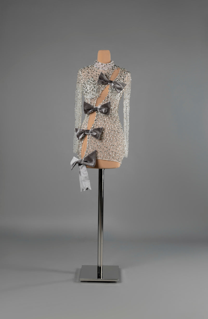Sihëna Argent Bows — silver high-neck long-sleeve fitted mini dress, crystal-beaded over sheer nude with a diagonal cutout and grey velvet bows.
