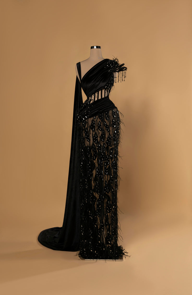 Sihëna Midnight Veil — black one-shoulder column gown with draped velvet bodice, sheer beaded midriff and skirt, feather trim and cape drape.