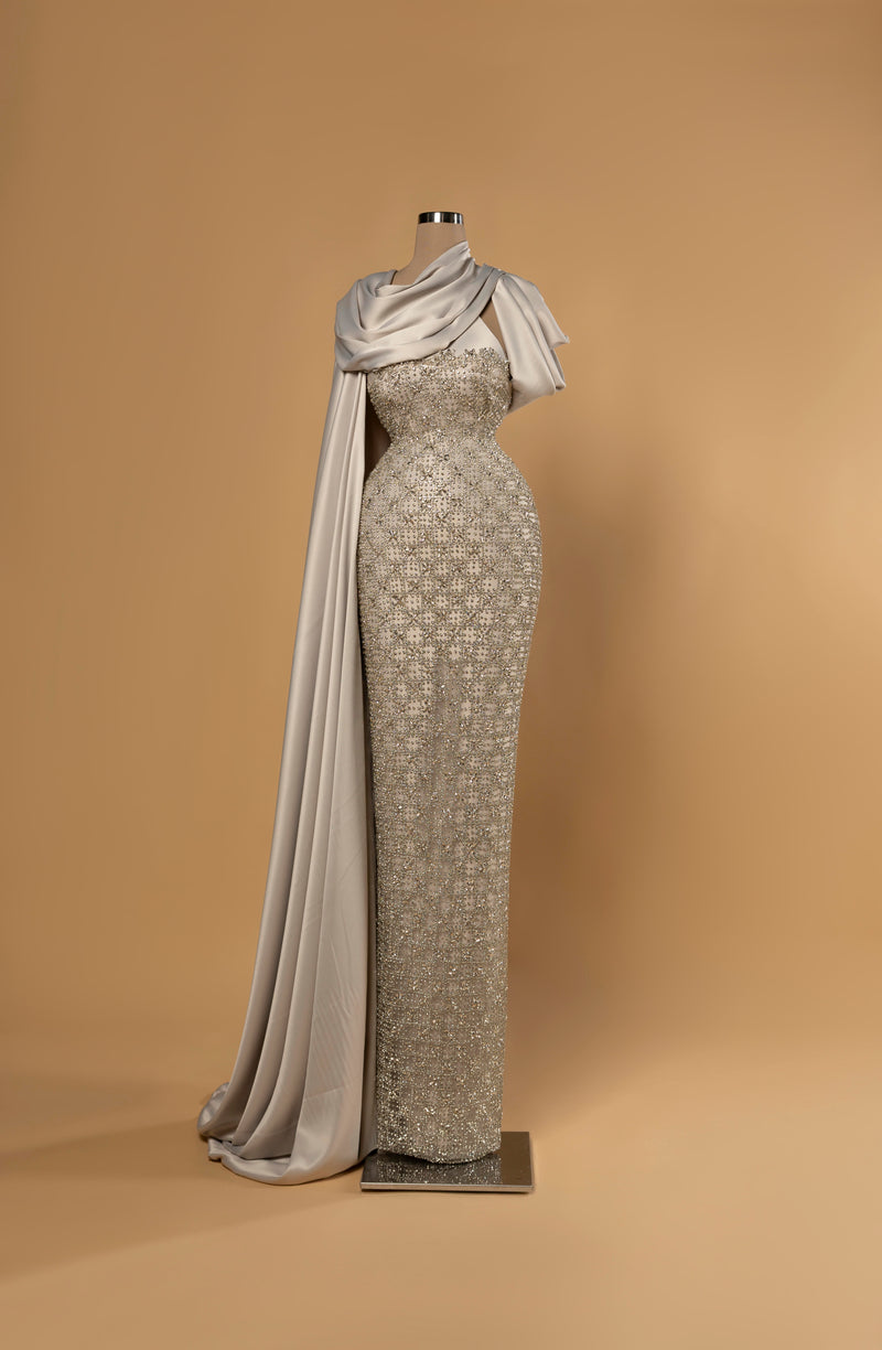 Sihëna Lunar Drape — silver strapless column gown densely crystal-beaded with a draped satin cowl cape over one shoulder.