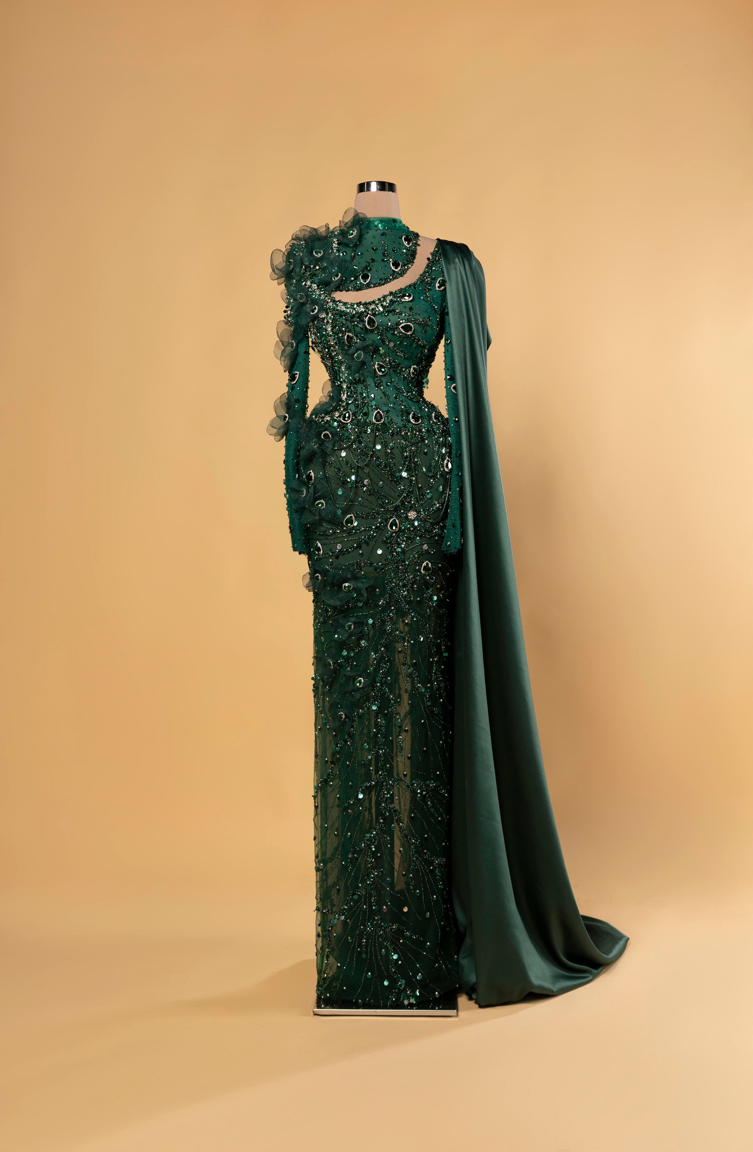 Sihëna Malachite Aura — emerald high-neck long-sleeve mermaid gown with teardrop crystal beadwork, 3D ruffle florals and one-shoulder satin cape drape.