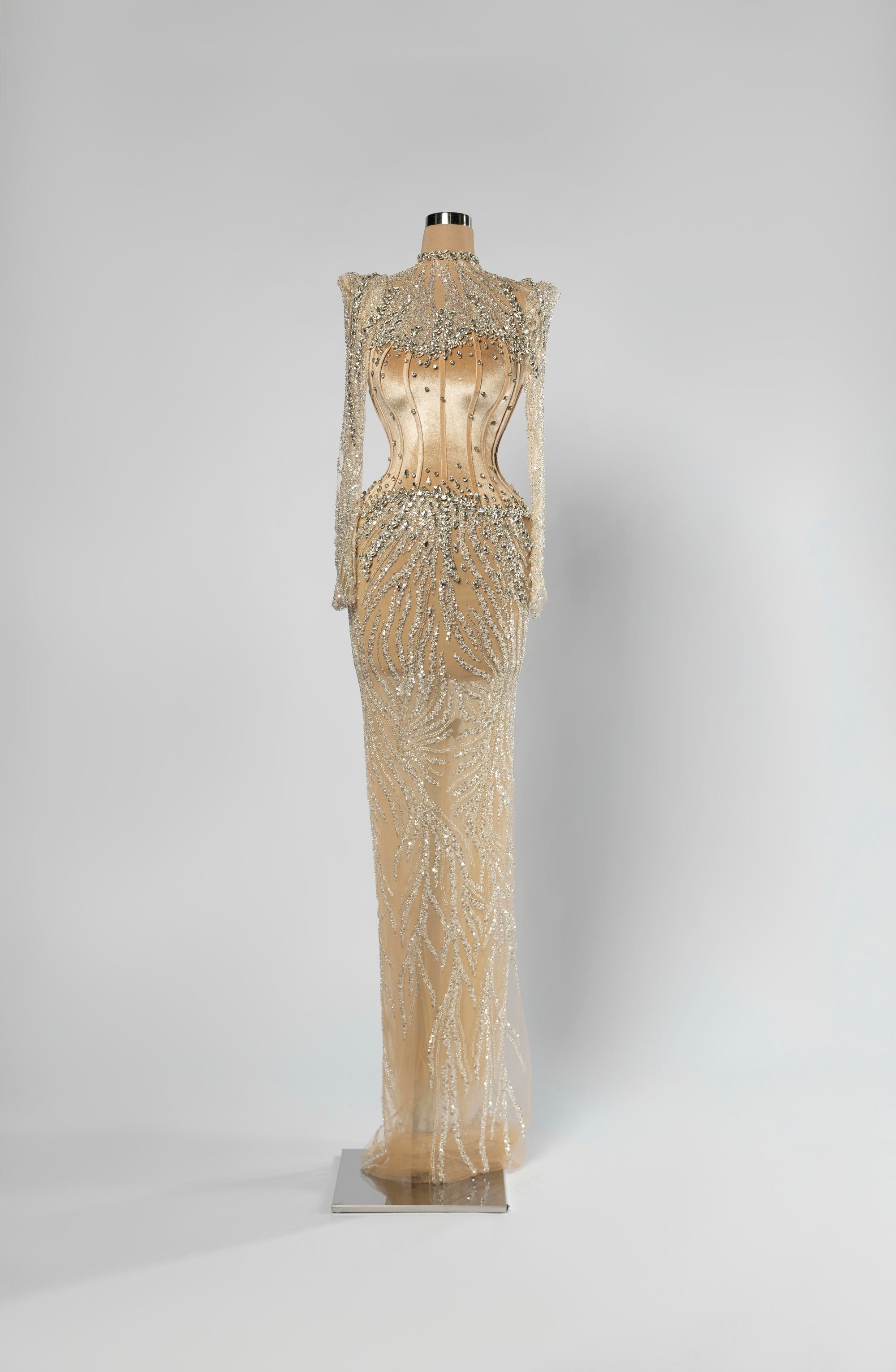Sihëna Auric Lattice — champagne high-neck long-sleeve column evening gown with crystal illusion shoulders and beaded sheer skirt over a corset.