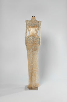 Sihëna Auric Lattice — champagne high-neck long-sleeve column evening gown with crystal illusion shoulders and beaded sheer skirt over a corset.