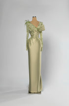 Sihëna Sage Meridian — sage-green asymmetric off-shoulder column evening gown in satin with beaded floral shoulder and feather accent.