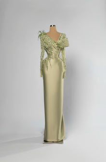 Sihëna Sage Meridian — sage-green asymmetric off-shoulder column evening gown in satin with beaded floral shoulder and feather accent.