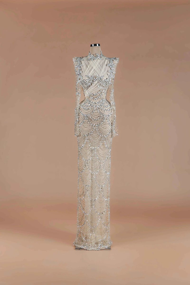 Sihëna Silver Scallop — silver high-neck long-sleeve column gown with scalloped crystal-pearl beadwork on sheer nude tulle.