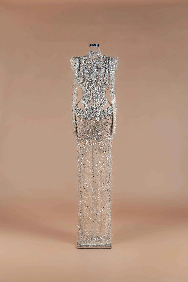 Sihëna Prismatic Cascade — silver high-neck long-sleeve column gown encrusted with crystal and beadwork on sheer nude tulle.