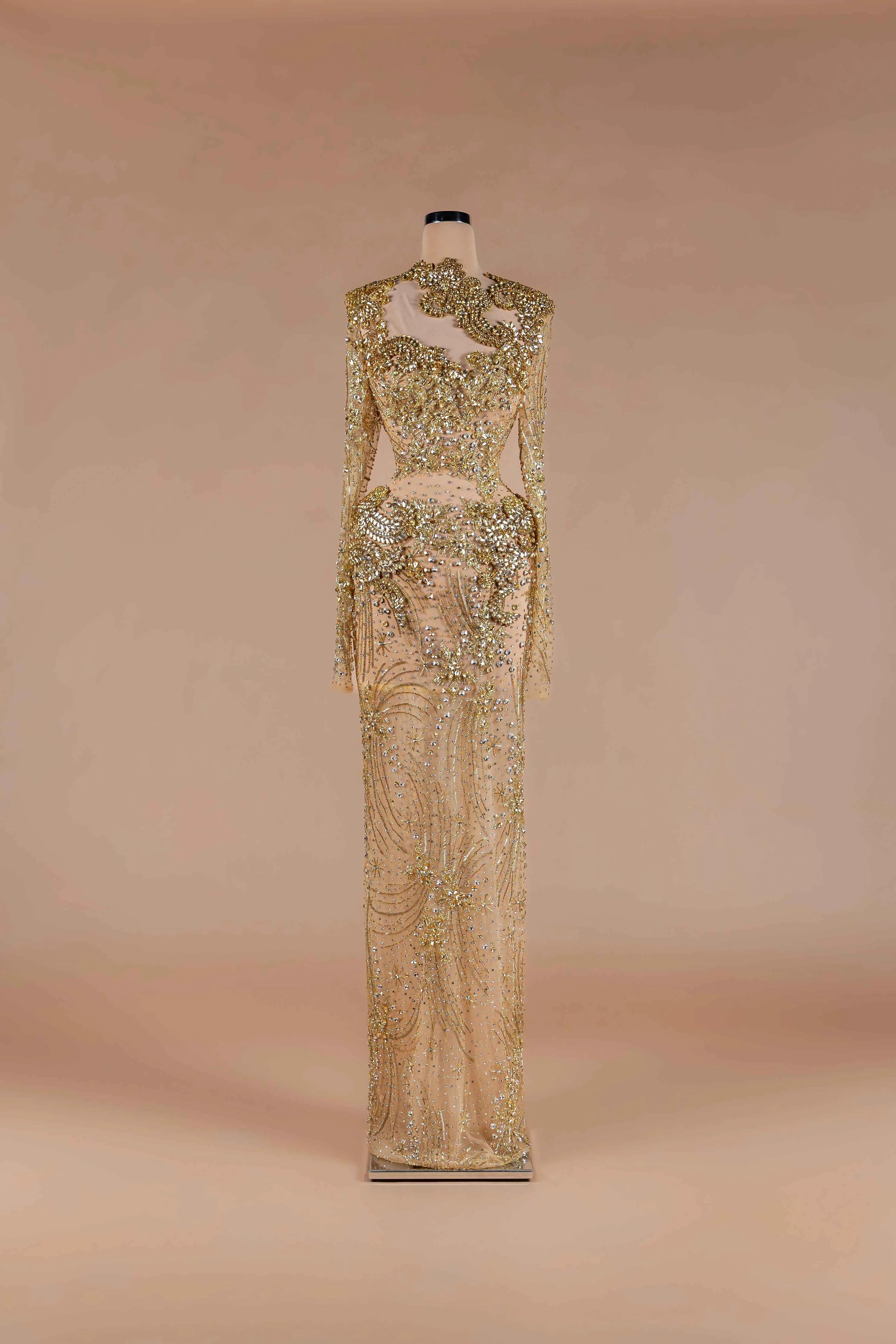Sihëna Aurelia Sovereign — gold high-neck long-sleeve column gown with crystal and gold beadwork on sheer nude tulle.