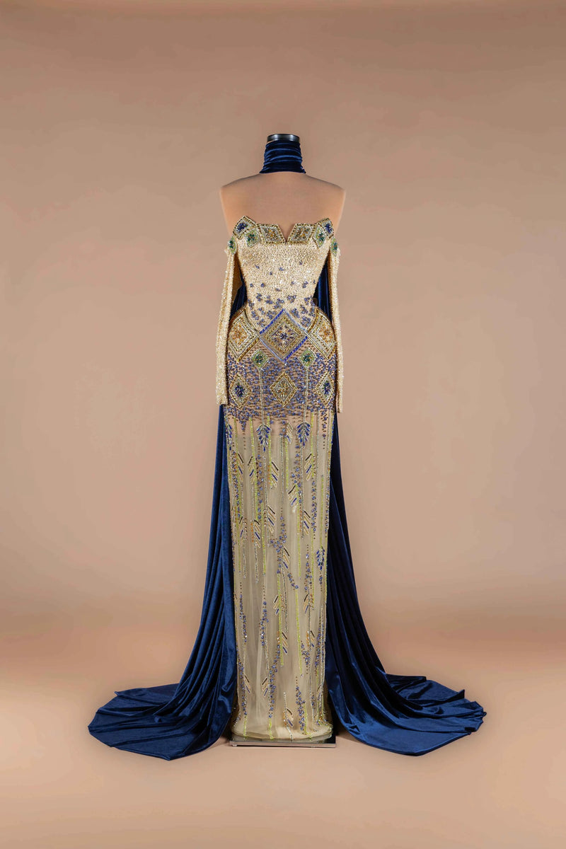 Sihëna Indigo Mosaic — navy strapless off-shoulder mermaid gown with gold-and-blue mosaic beadwork and navy velvet cape train.