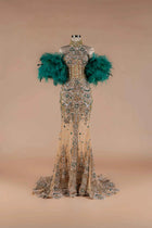 Sihëna Teal Sovereign — emerald high-neck off-shoulder mermaid gown with gold-and-emerald crystal beadwork and emerald feather sleeves.