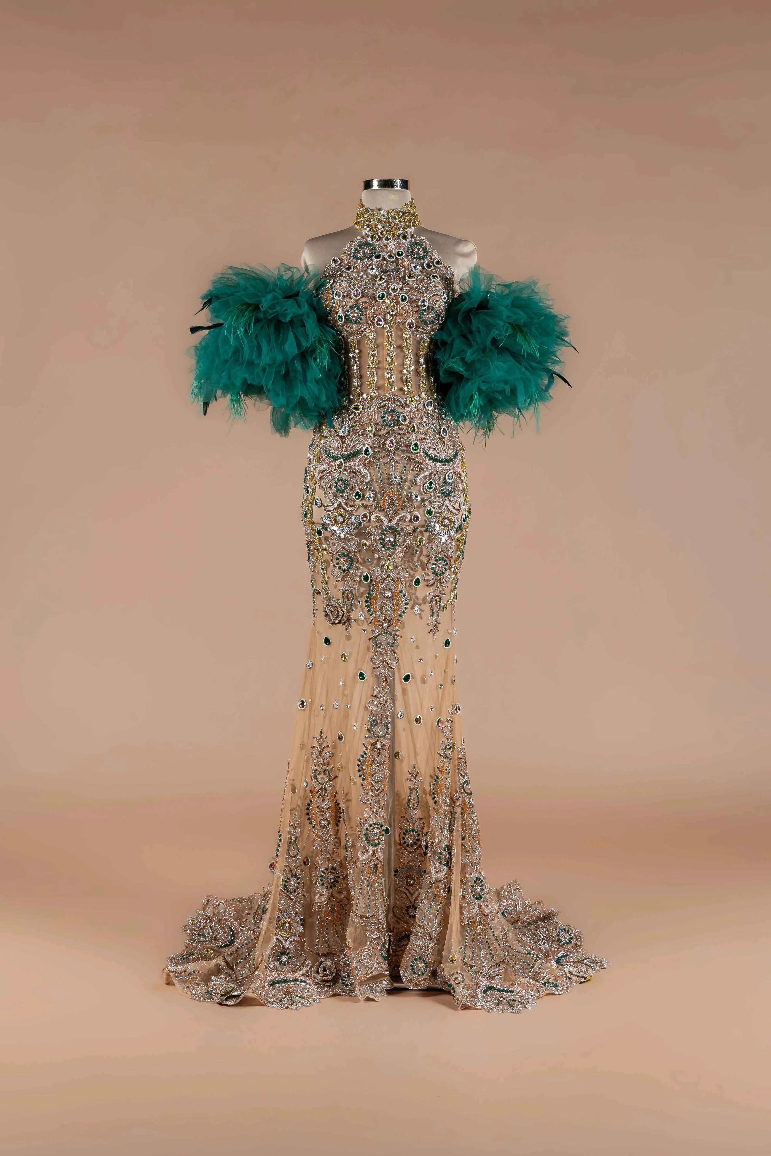 Sihëna Teal Sovereign — emerald high-neck off-shoulder mermaid gown with gold-and-emerald crystal beadwork and emerald feather sleeves.