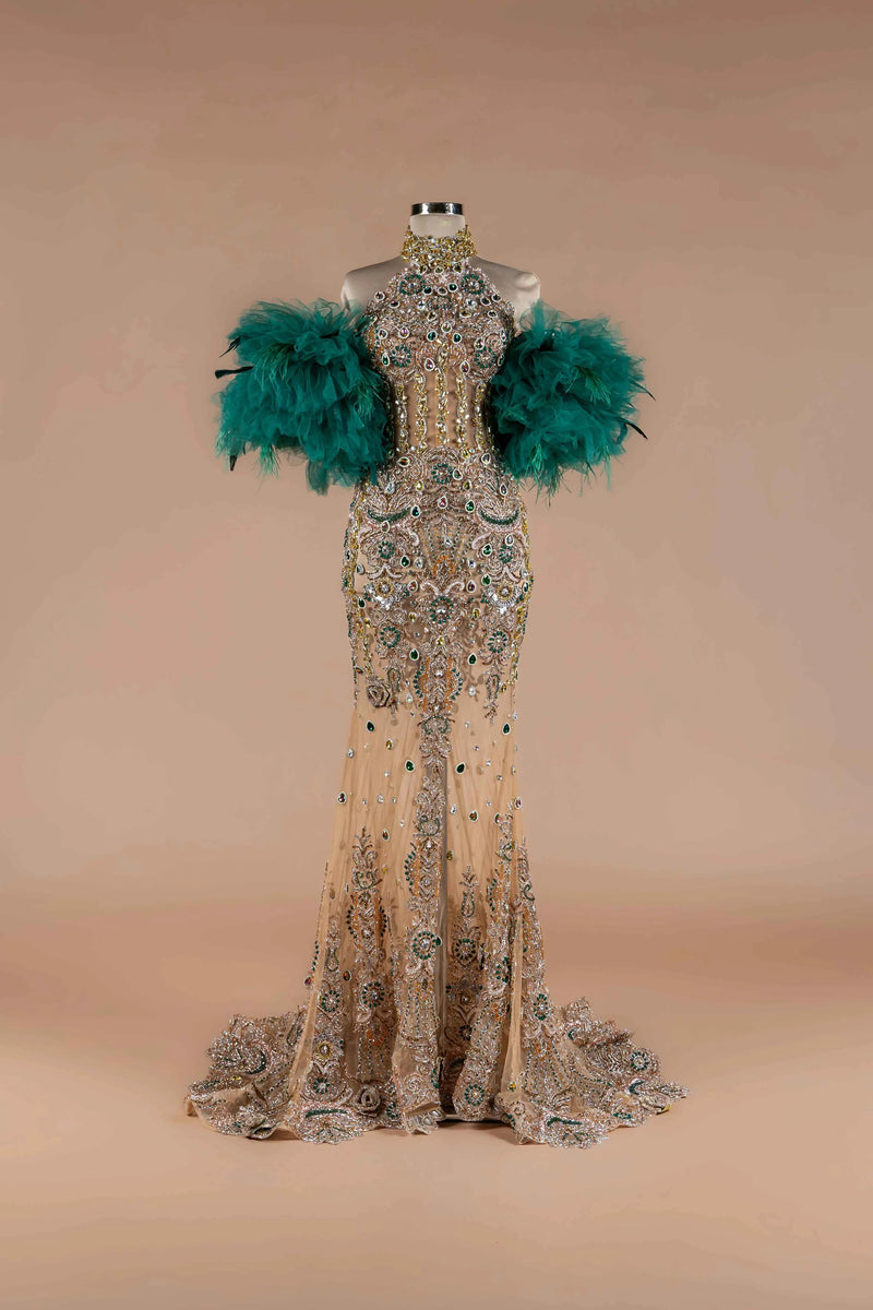 Sihëna Teal Sovereign — emerald high-neck off-shoulder mermaid gown with gold-and-emerald crystal beadwork and emerald feather sleeves.