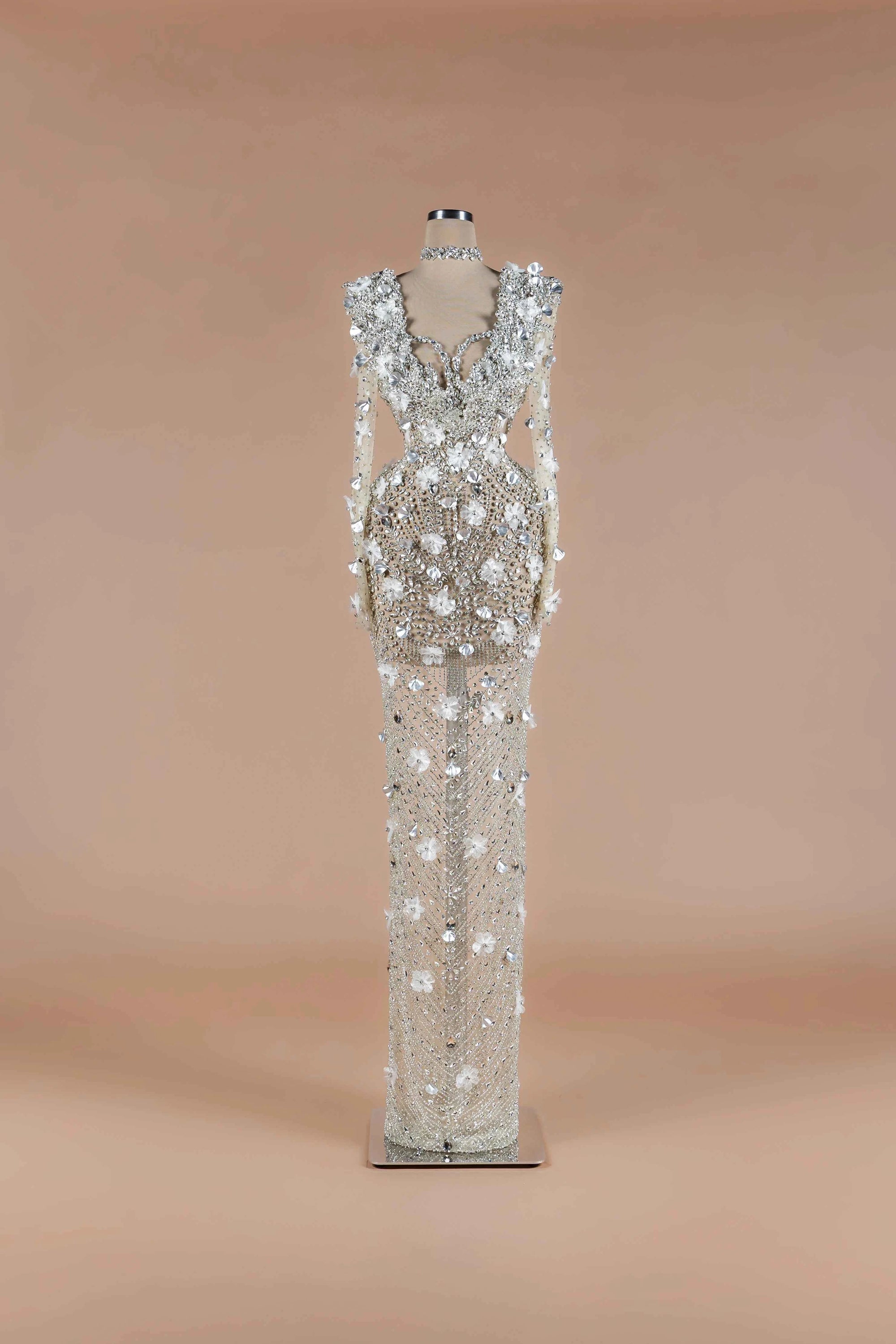 Sihëna Crystalline Garden — silver high-neck long-sleeve column gown with all-over crystal beadwork and 3D white floral appliqué.