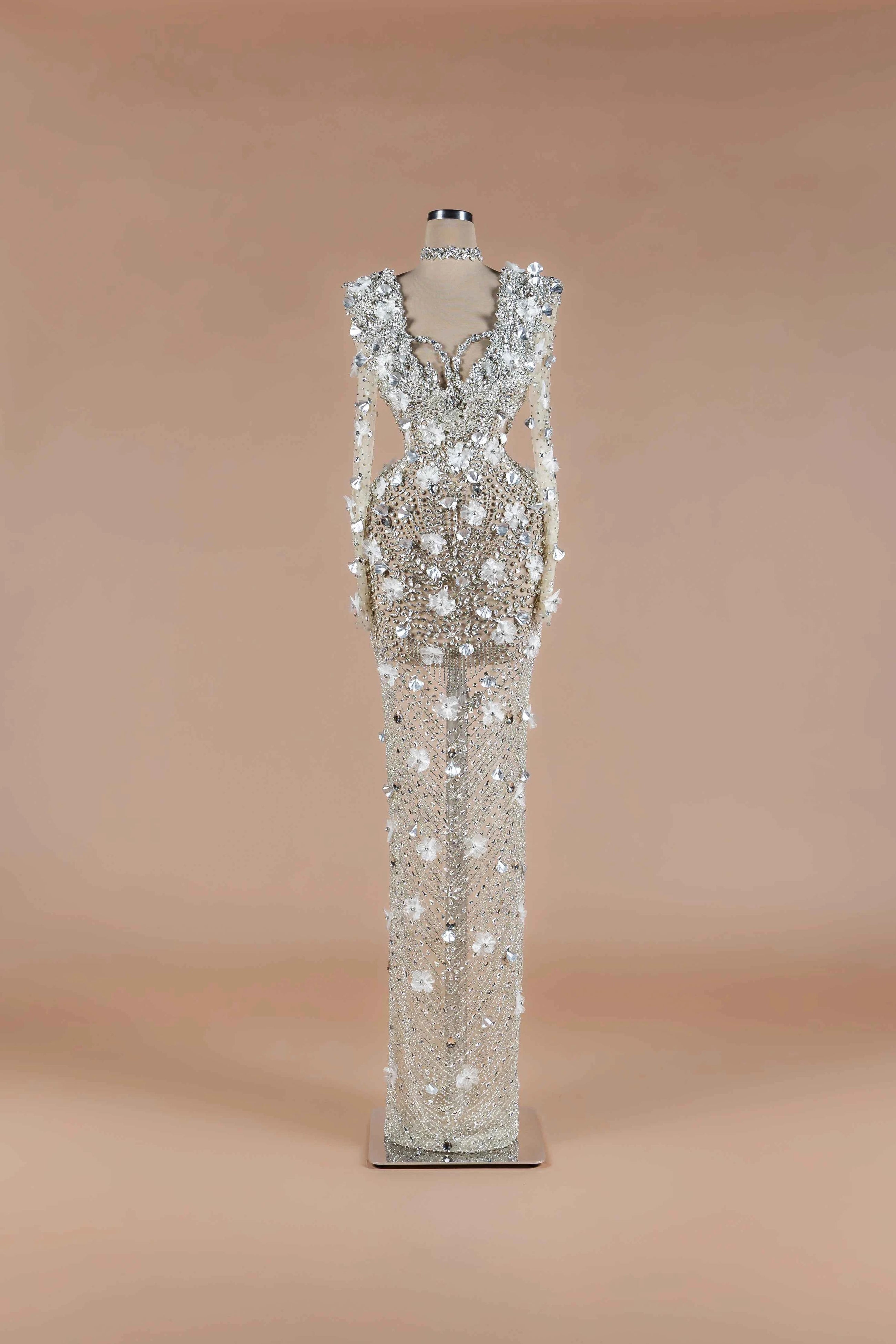 Sihëna Crystalline Garden — silver high-neck long-sleeve column gown with all-over crystal beadwork and 3D white floral appliqué.