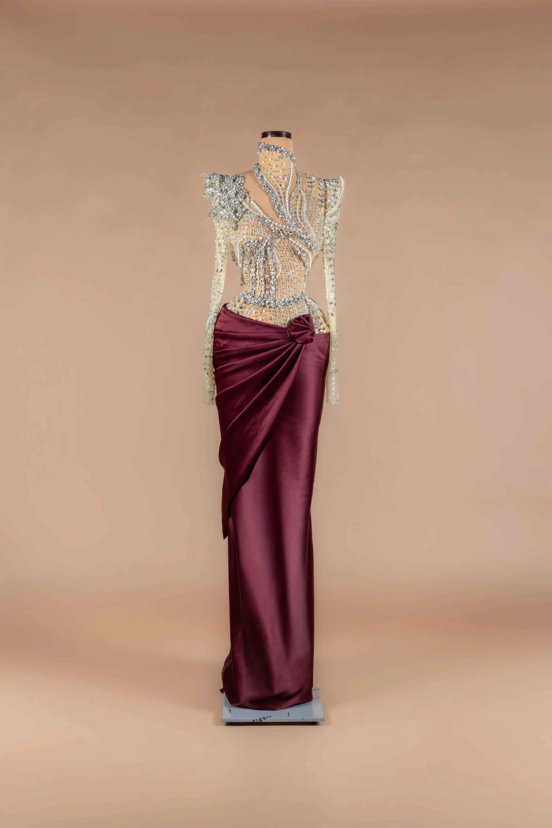 Sihëna Bordeaux Prism — burgundy high-neck long-sleeve column gown with crystal-beaded sheer bodice and draped satin wrap skirt.
