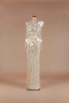 Sihëna Ivory Camellia — champagne high-neck long-sleeve sheer lace gown with silver beadwork and ivory 3D camellia florals.