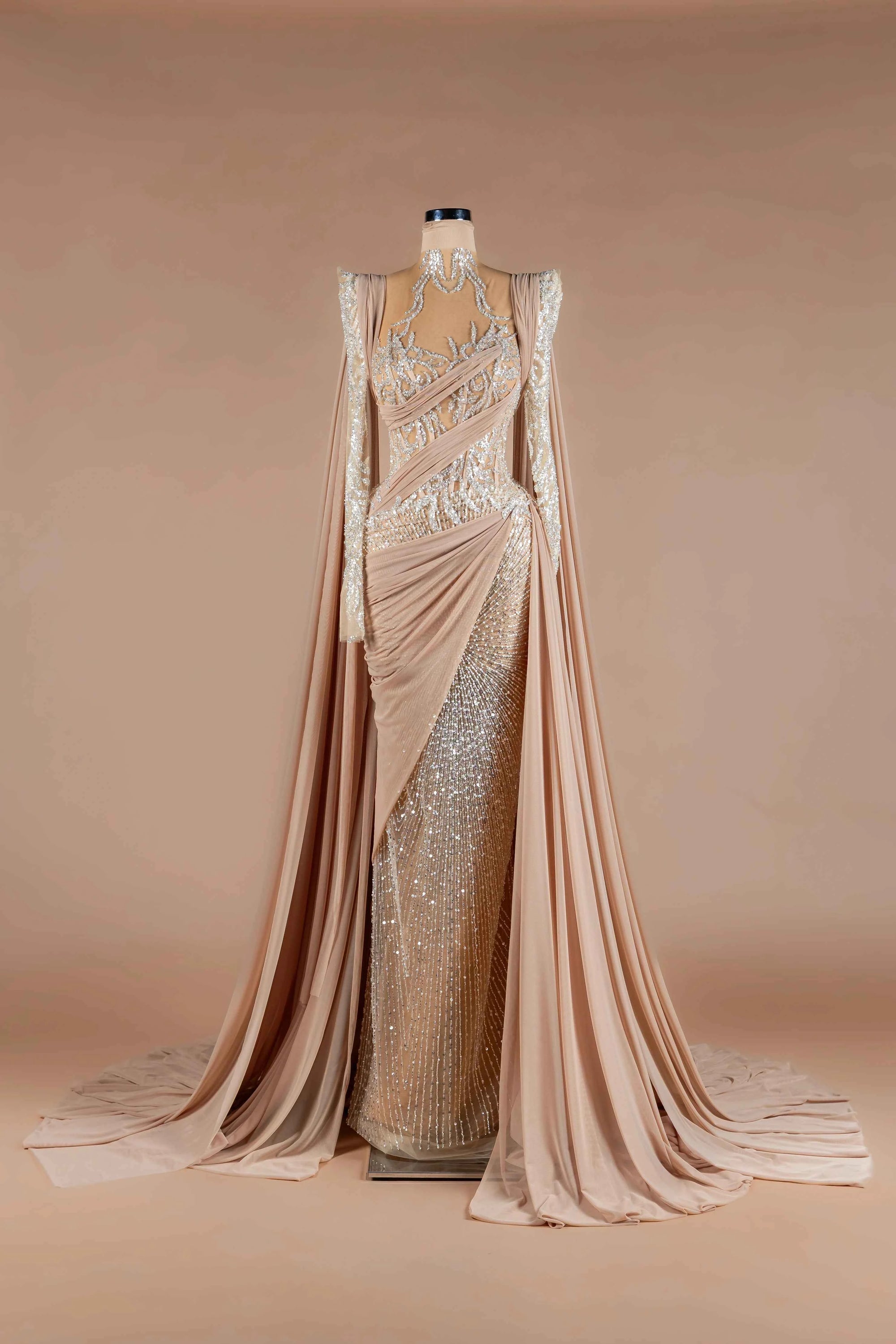 Sihëna Nude Athena — nude high-neck long-sleeve mermaid gown with silver sequin beadwork, draped chiffon sash and high slit.