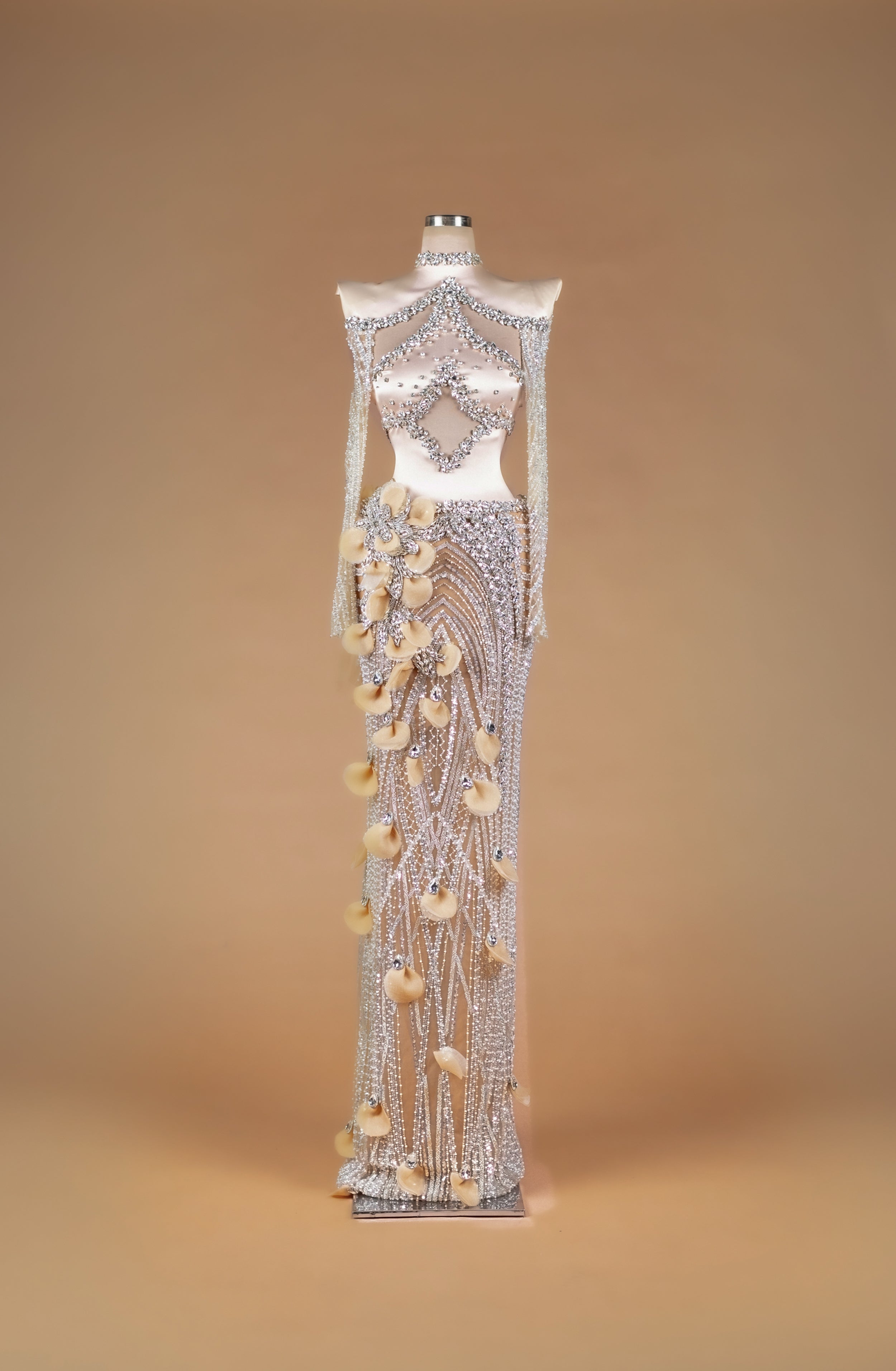 Sihëna Crystal Petal Tapestry — silver high-neck off-shoulder crystal-beaded illusion column gown with large midriff cutout and 3D organza petals.