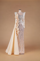 Sihëna Emerald Relic Couture — champagne high-neck long-sleeve crystal-beaded illusion column gown with organza ruffle cascade and overskirt train.