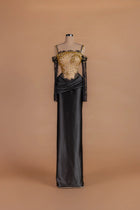 Sihëna Ember Eventide — black square-neck off-shoulder column gown with gold crystal beading on a sheer bodice.